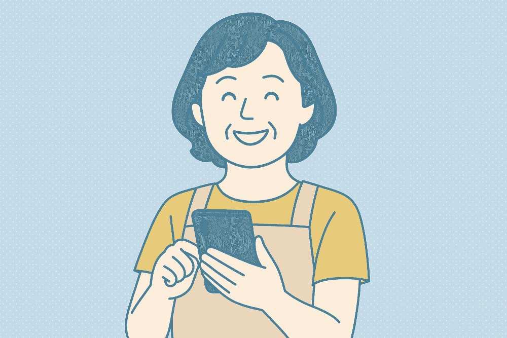 スマホ操作に慣れ、笑顔で使いこなしている50代女性介護士のイラスト。エプロン姿で明るい表情を見せ、自信を持ってスマートフォンを操作している様子が描かれている。