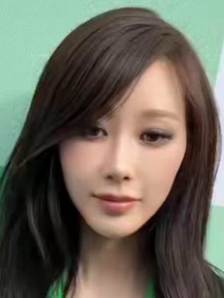 緑色の背景の前で下を向き気味の長い黒髪のジゼルの写真