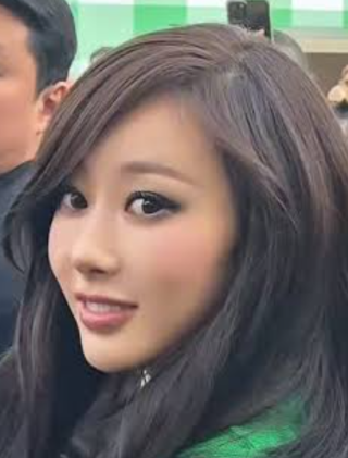 緑色の背景の前で振り向く長い黒髪のジゼルの顔写真