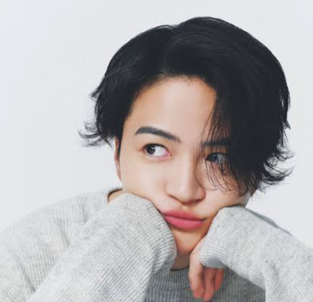 黒髪の人物がグレーのニットを着て、両手で頬杖をつきながら横目で見つめているプロフィール写真。