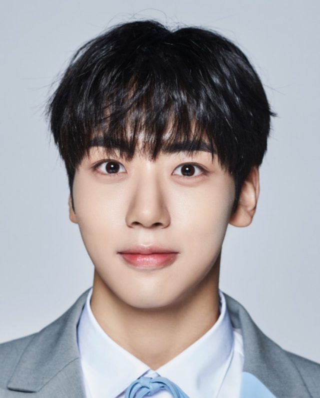 黒髪の人物がグレーのスーツと水色のネクタイを身につけ、正面を向いているプロフィール写真。