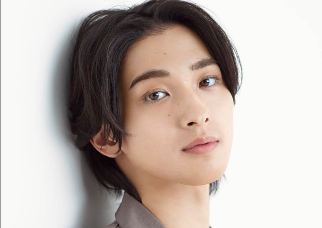 白い背景の前で横向き気味に顔を見せる人物のポートレート写真。センターパートの黒髪と整った眉、やわらかな表情が印象的です。