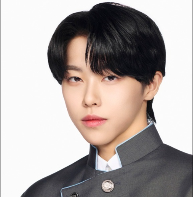 黒髪の若い男性が制服風の衣装を着て、落ち着いた表情で正面を見つめている写真