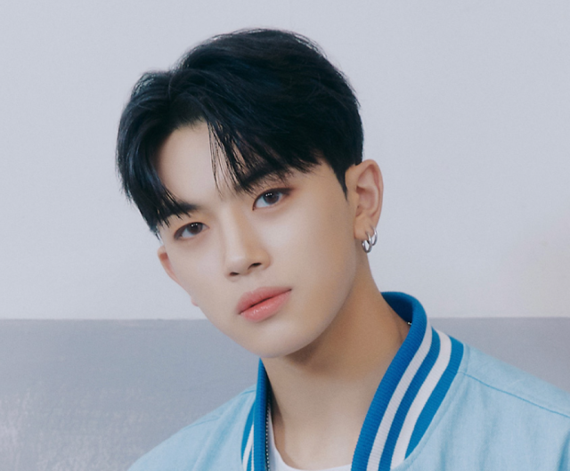 黒髪の若い男性が水色のジャケットを着て、やわらかい表情でカメラを見つめている顔写真