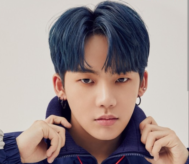 青みがかった黒髪の若い男性が、両手で襟元を持ちながら正面を見つめている顔写真