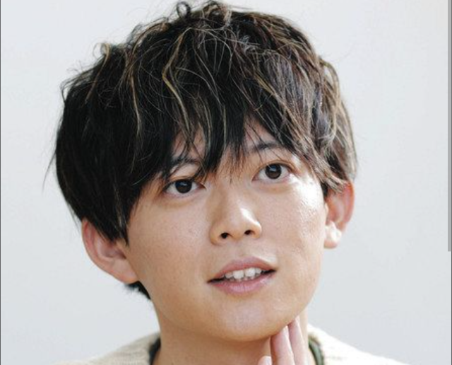 松丸亮吾の顔がよくわかる上半身アップ画像。黒髪で少し上を見ながら、指をあご元に添えている様子