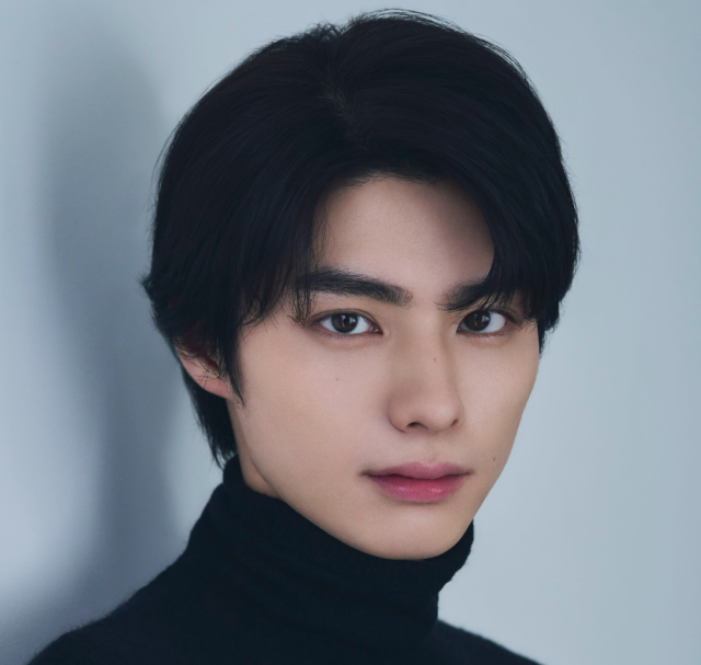 黒いタートルネックを着た本田響矢が、淡いグレーの背景の前でこちらを見つめているバストアップ画像。印象的な目元と整った口元がよく分かります。
