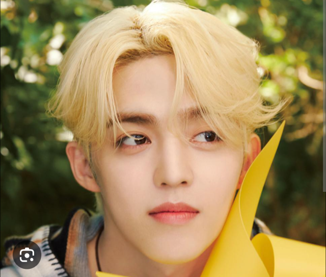 金髪の人物が屋外で横目を向けているポートレート画像