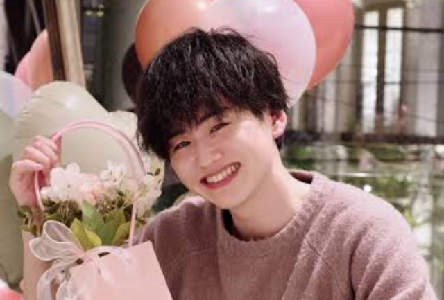 花束を手に笑顔を見せるトミーの上半身画像。黒髪とやさしい表情が印象的な写真