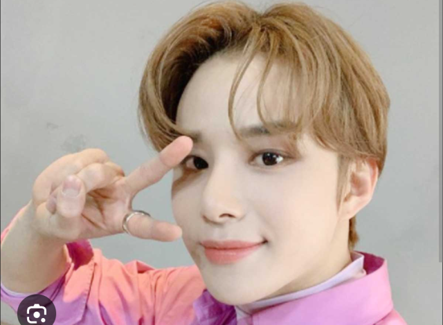 ピンクの衣装を着てピースサインを見せるジョンウの上半身画像。大きな目元とやわらかな表情が印象的な写真
